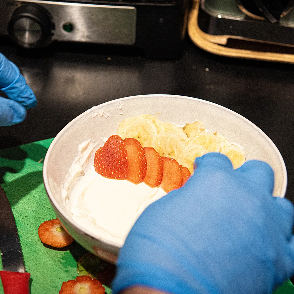 A yogurt bowl being made with strawberries and banana