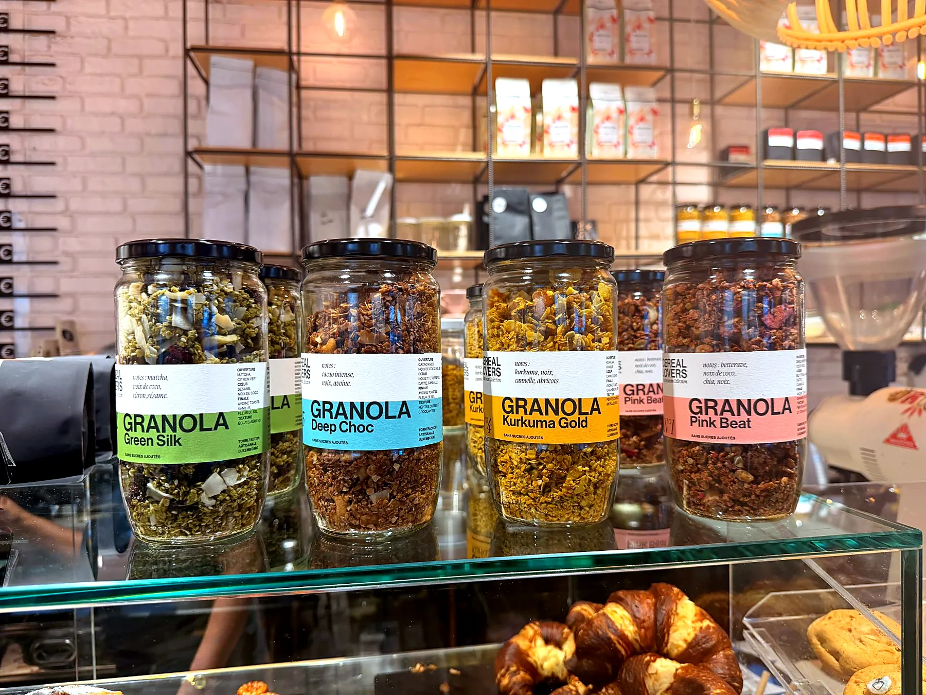 The four granola jars side by side on the counter: Green Silk, Deep Choc, Kurkuma Gold, Pink Beat